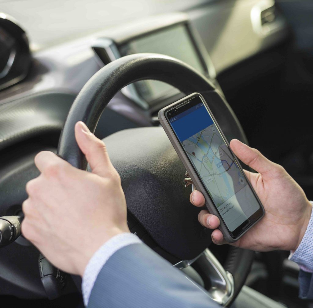 Client d'affaires utilisant son smartphone confortablement installé dans une voiture VTC haut de gamme de Transferts Paris