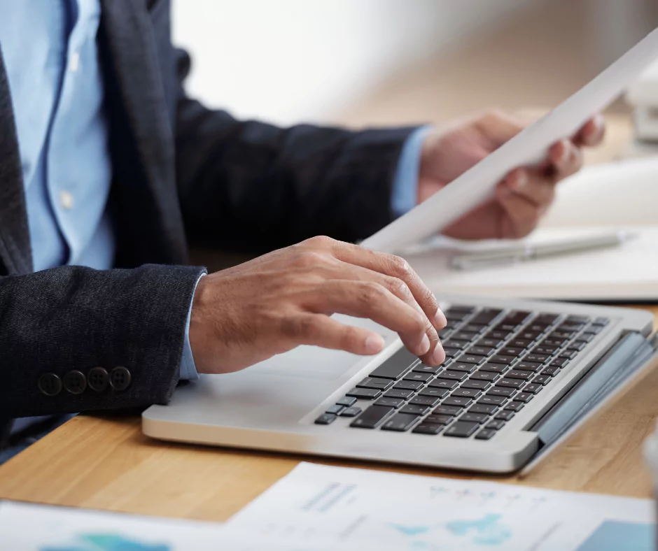 Professionnel complétant inscription au registre des exploitants VTC sur ordinateur avec documents administratifs