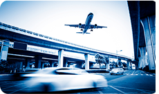 Vue d'une route urbaine avec des voitures rapides et un avion au-dessus, illustrant le service de transfert aéroport.